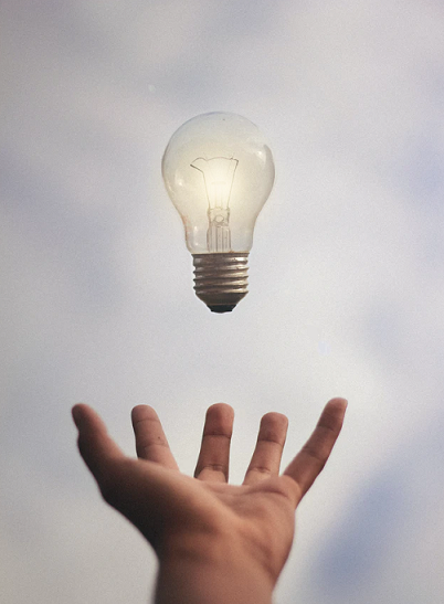 Light bulb falling into open hand.